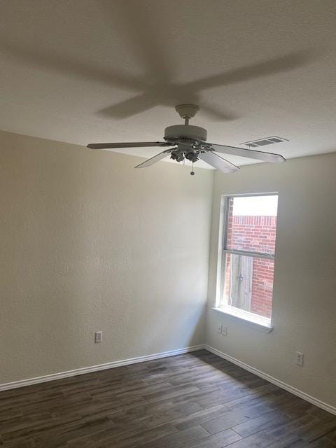 empty room with dark wood finished floors, ceiling fan, and baseboards