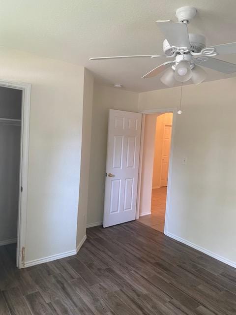 unfurnished bedroom featuring dark wood finished floors, baseboards, a ceiling fan, and a closet