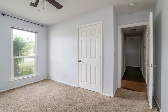 unfurnished bedroom featuring carpet, multiple windows, and baseboards