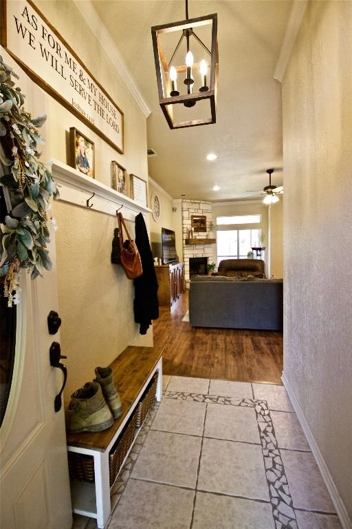 2502 Joseph Dr, Copperas Cove, TX 76522 - mudroom featuring crown molding, a chandelier, a stone fireplace, tile patterned flooring, and baseboards