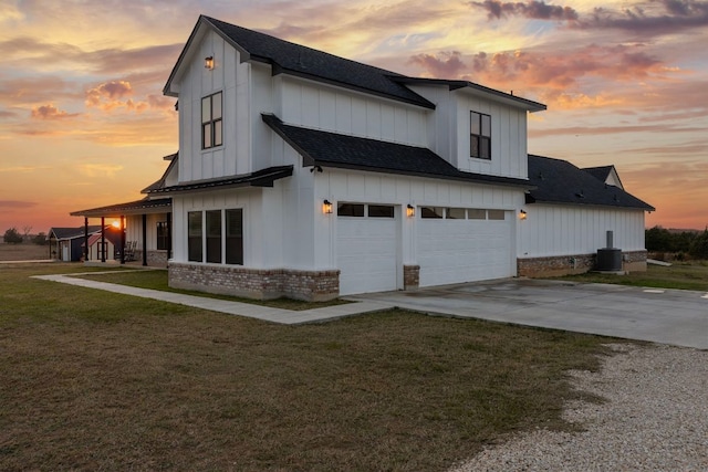 479 Brown Rd, Mcdade, TX 78650 - property exterior at dusk with an attached garage, driveway, a shingled roof, board and batten siding, and brick siding