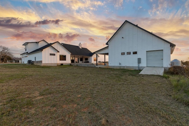 479 Brown Rd, Mcdade, TX 78650 - back of house at dusk with board and batten siding, a yard, a patio area, and central AC