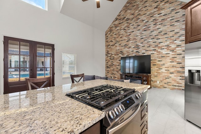 479 Brown Rd, Mcdade, TX 78650 - kitchen with stainless steel appliances, high vaulted ceiling, a ceiling fan, light stone counters, and brick wall