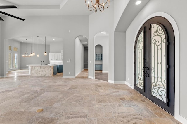8295 Lime Creek Rd, Volente, TX 78641 - foyer entrance featuring a chandelier, high vaulted ceiling, stone tile flooring, french doors, and baseboards
