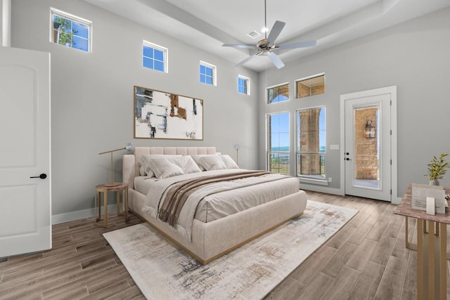 8295 Lime Creek Rd, Volente, TX 78641 - bedroom featuring access to outside, a tray ceiling, wood finished floors, a towering ceiling, and baseboards