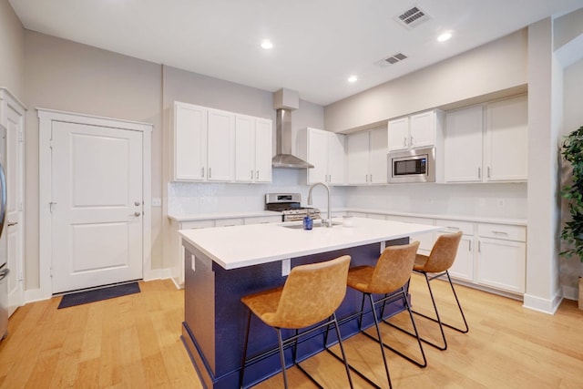 2520 Bluebonnet Ln Unit 41, Austin, TX 78704 - kitchen featuring wall chimney exhaust hood, appliances with stainless steel finishes, light wood-style floors, a center island with sink, and recessed lighting