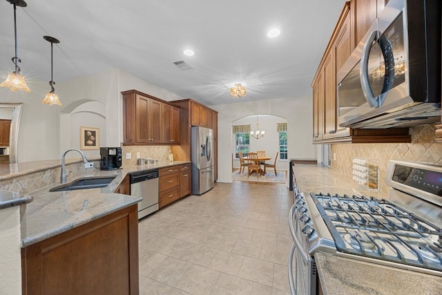 2518 Nightshade Dr, Cedar Park, TX 78613 - kitchen featuring appliances with stainless steel finishes, arched walkways, a chandelier, light stone counters, and decorative backsplash