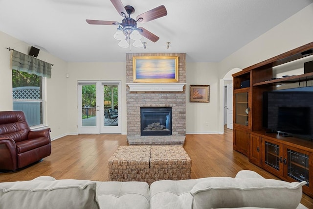 2518 Nightshade Dr, Cedar Park, TX 78613 - living room featuring wood finished floors, a ceiling fan, a fireplace, and arched walkways