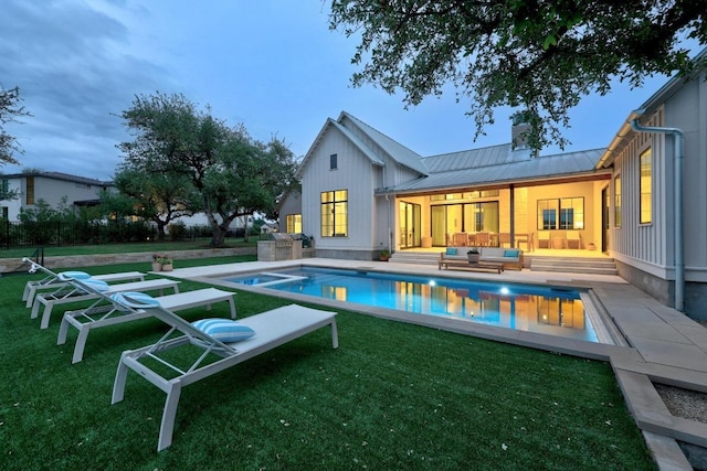 back of house with an outdoor living space, a chimney, a lawn, metal roof, and a standing seam roof