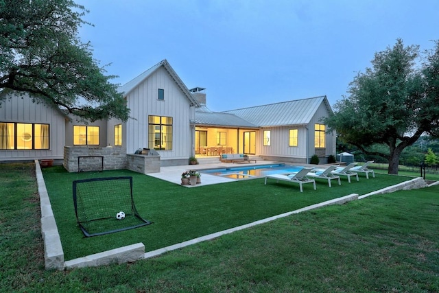 rear view of property with board and batten siding, metal roof, an outdoor pool, a yard, and a chimney