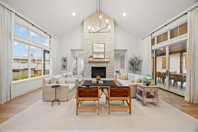 living room featuring high vaulted ceiling, wood finished floors, a stone fireplace, healthy amount of natural light, and beam ceiling