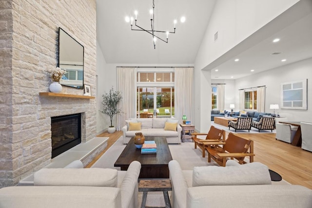 living area featuring high vaulted ceiling, wood finished floors, a chandelier, a fireplace, and recessed lighting