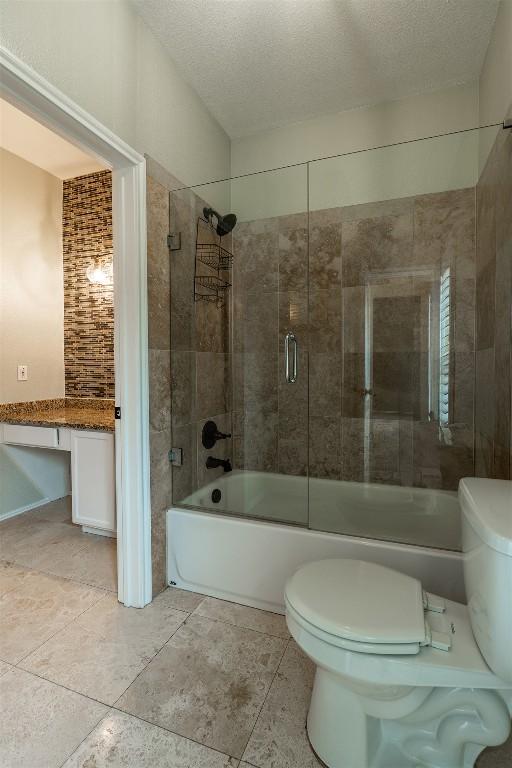 8610 Axis Dr, Austin, TX 78749 - full bath featuring toilet, enclosed tub / shower combo, a textured ceiling, and tile patterned flooring