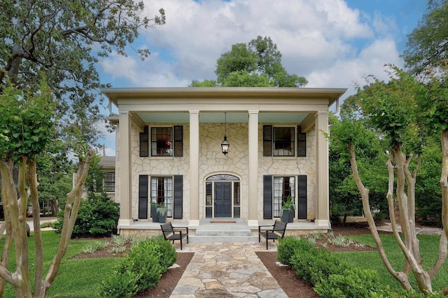 rear view of property featuring covered porch and stone siding