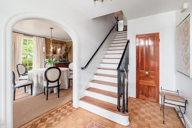 stairs featuring a chandelier and arched walkways