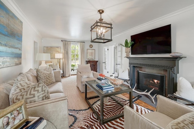 living room featuring ornamental molding, a glass covered fireplace, and a chandelier