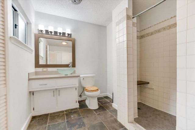 3508 Winfield Cv, Austin, TX 78704 - bathroom with a tile shower, toilet, vanity, a textured ceiling, and baseboards