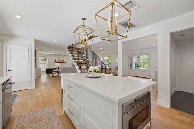 3115 Thousand Oaks Dr, Austin, TX 78746 - kitchen featuring appliances with stainless steel finishes, light wood-type flooring, white cabinetry, a center island, and decorative light fixtures