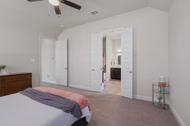 bedroom with lofted ceiling, light carpet, baseboards, connected bathroom, and a ceiling fan