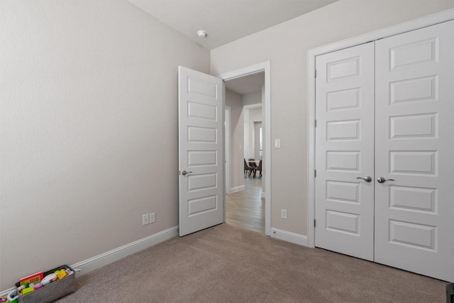 unfurnished bedroom with carpet flooring, baseboards, and a closet