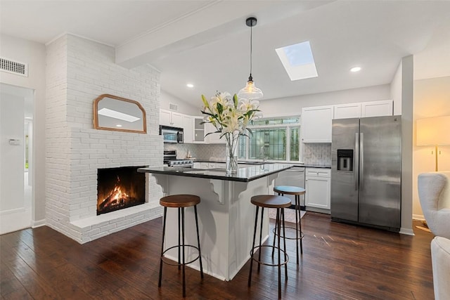 1513 Westover Rd, Austin, TX 78703 - kitchen with appliances with stainless steel finishes, dark countertops, a breakfast bar area, white cabinetry, and tasteful backsplash