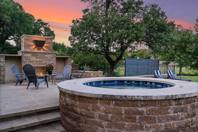 209 Ridge View Dr, Georgetown, TX 78628 - pool at dusk featuring an outdoor brick fireplace, an outdoor hot tub, and a patio