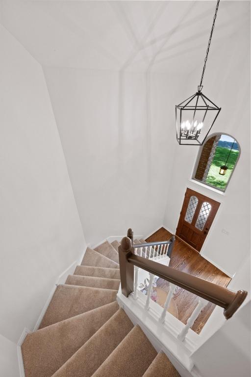 6304 John Chisum Ln, Austin, TX 78749 - stairs featuring a chandelier, wood finished floors, and baseboards