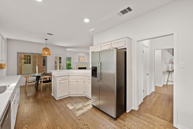 6304 John Chisum Ln, Austin, TX 78749 - kitchen featuring appliances with stainless steel finishes, a peninsula, light wood finished floors, white cabinetry, and recessed lighting