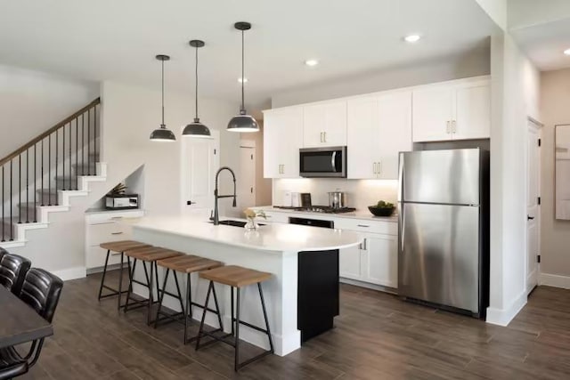 237 Regatta Trl, Leander, TX 78641 - kitchen featuring stainless steel appliances, a sink, dark wood finished floors, a kitchen island with sink, and a breakfast bar area