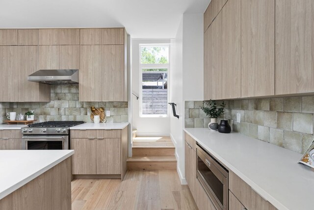 2903 Breeze Ter Unit 1, Austin, TX 78722 - kitchen with stainless steel appliances, range hood, modern cabinets, light brown cabinets, and light wood-type flooring