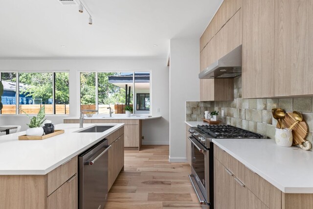 2903 Breeze Ter Unit 1, Austin, TX 78722 - kitchen with stainless steel appliances, modern cabinets, under cabinet range hood, and light brown cabinetry