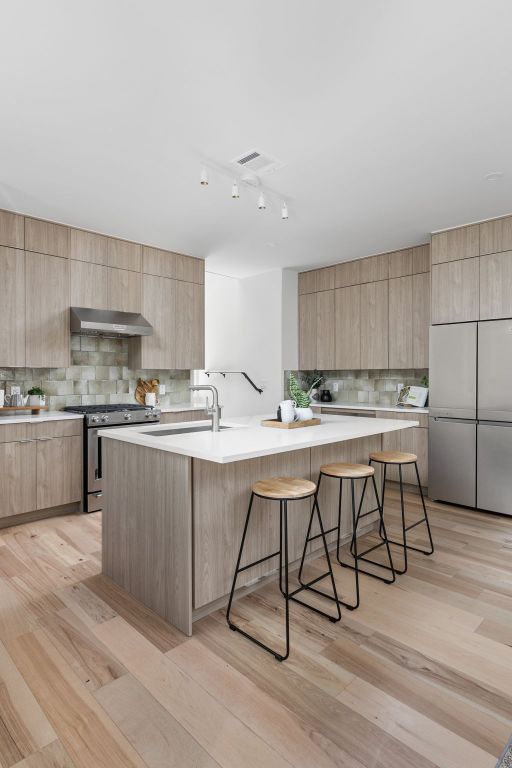 2903 Breeze Ter Unit 1, Austin, TX 78722 - kitchen with stainless steel appliances, modern cabinets, light brown cabinetry, decorative backsplash, and extractor fan