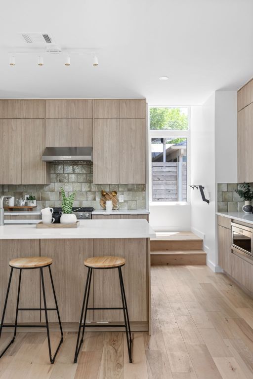 2903 Breeze Ter Unit 1, Austin, TX 78722 - kitchen with a kitchen bar, modern cabinets, ventilation hood, and light brown cabinetry
