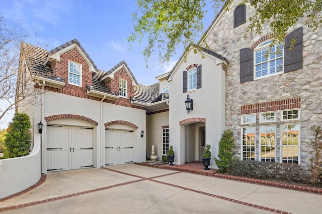 124 Florentine, Horseshoe Bay, TX 78657 - view of front of property with driveway, stucco siding, stone siding, a garage, and a tile roof
