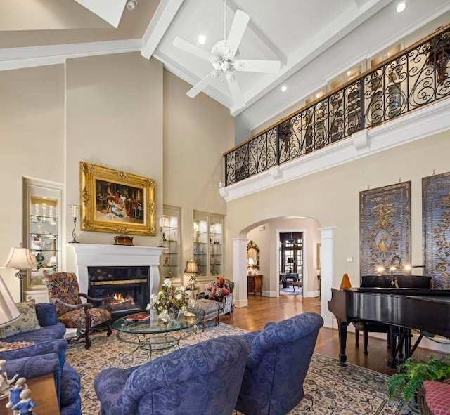 124 Florentine, Horseshoe Bay, TX 78657 - living room featuring arched walkways, ornate columns, a glass covered fireplace, high vaulted ceiling, and beamed ceiling