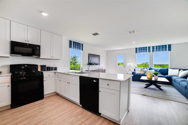 1006 Antelope Trl, Temple, TX 76504 - kitchen with black appliances, open floor plan, a peninsula, a sink, and light wood finished floors