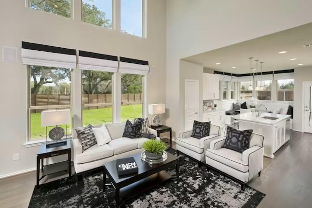 living area with a towering ceiling and dark wood-style floors
