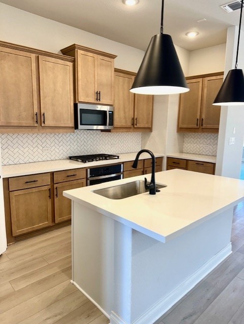 999 N Roger Hanks Pkwy, Dripping Springs, TX 78620 - kitchen with stainless steel microwave, a sink, black gas cooktop, light wood-style floors, and backsplash
