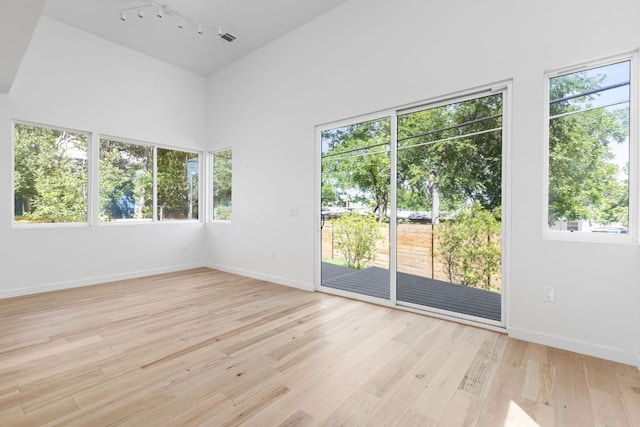 spare room with plenty of natural light, light wood-style floors, baseboards, and rail lighting