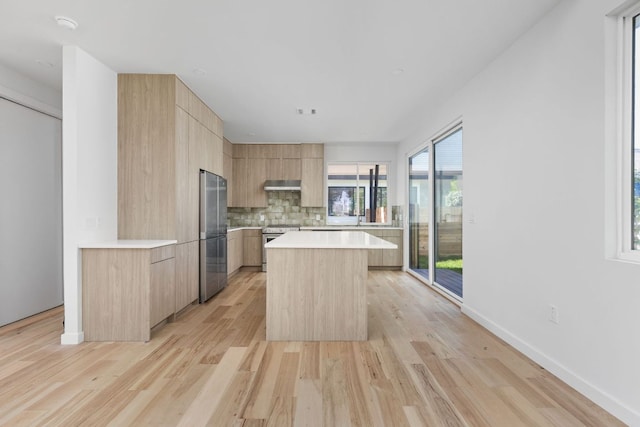 kitchen with appliances with stainless steel finishes, light brown cabinetry, modern cabinets, ventilation hood, and light countertops