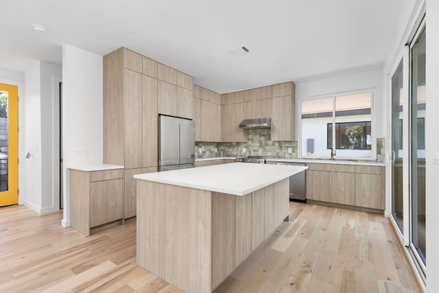 kitchen with stainless steel appliances, light brown cabinets, and modern cabinets