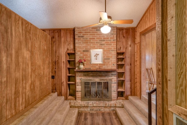 508 Lee St N, Round Rock, TX 78664 - unfurnished living room featuring wood walls, ceiling fan, stairway, a fireplace, and a textured ceiling