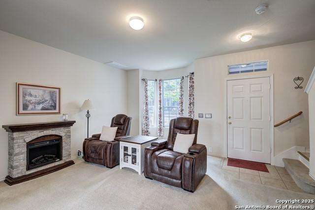 5659 Fergus Unit A, Kyle, TX 78640 - sitting room featuring light colored carpet, stairs, and a stone fireplace