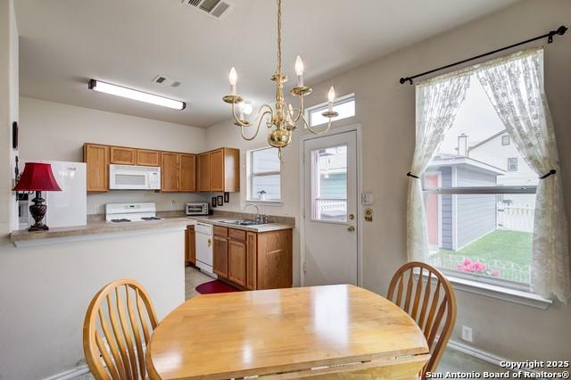 5659 Fergus Unit A, Kyle, TX 78640 - kitchen with white appliances, a chandelier, light countertops, brown cabinetry, and pendant lighting