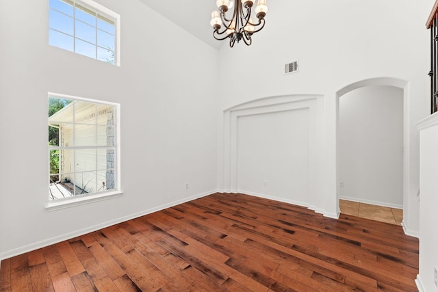 12501 Rush Creek Ln, Austin, TX 78732 - unfurnished room with a chandelier, hardwood / wood-style flooring, high vaulted ceiling, arched walkways, and baseboards