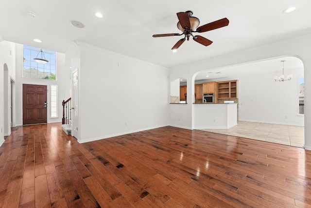 12501 Rush Creek Ln, Austin, TX 78732 - unfurnished living room featuring arched walkways, light wood finished floors, a chandelier, ceiling fan, and recessed lighting