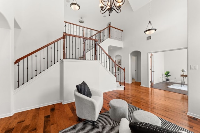 12501 Rush Creek Ln, Austin, TX 78732 - living room featuring arched walkways, a high ceiling, stairway, hardwood / wood-style flooring, and a chandelier