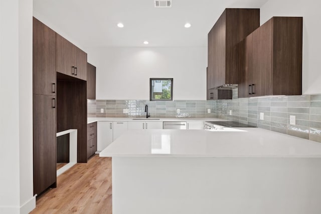 kitchen featuring a sink, modern cabinets, light countertops, dishwasher, and a peninsula