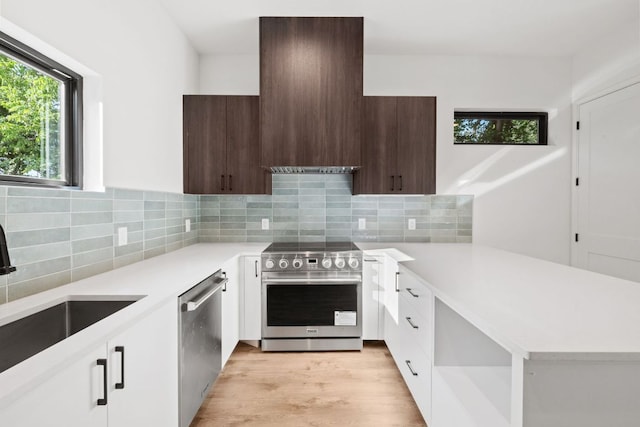 kitchen with stainless steel appliances, modern cabinets, light countertops, a sink, and white cabinets