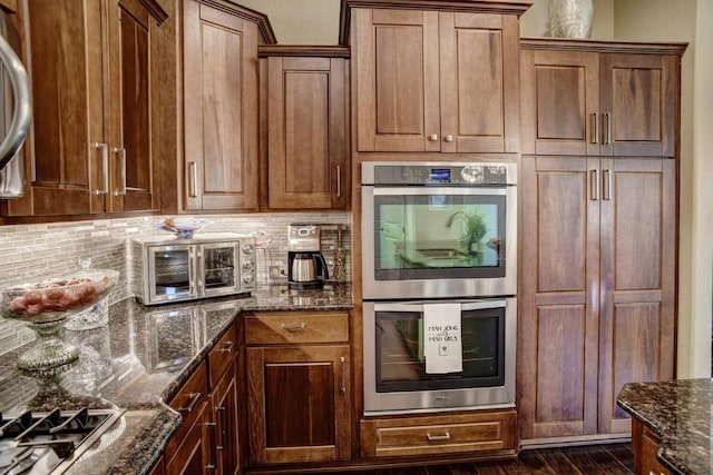 15208 Origins Ln, Austin, TX 78734 - kitchen featuring stainless steel appliances, decorative backsplash, dark stone countertops, and dark wood finished floors